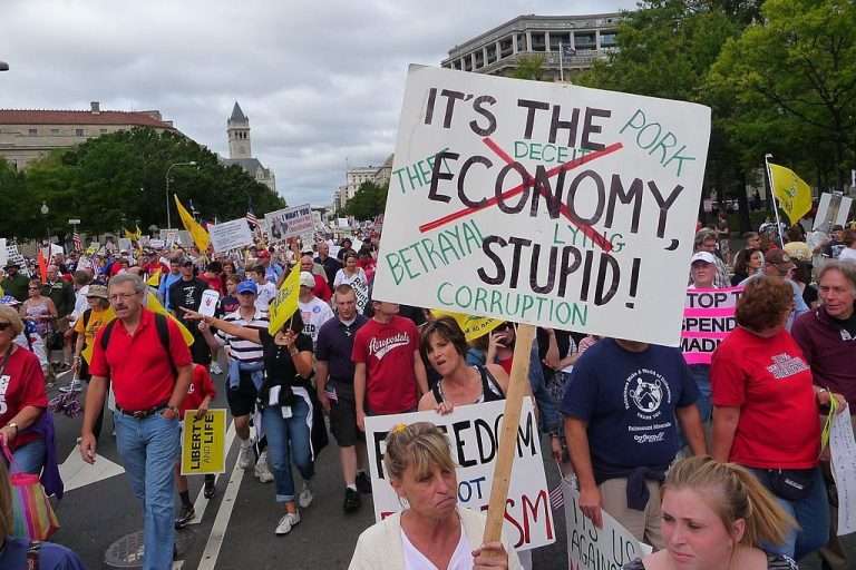 Protestors holding signs. "It's the economy, stupid."