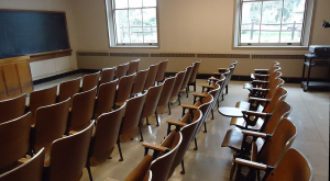 Chairs facing a blackboard in a classroom.