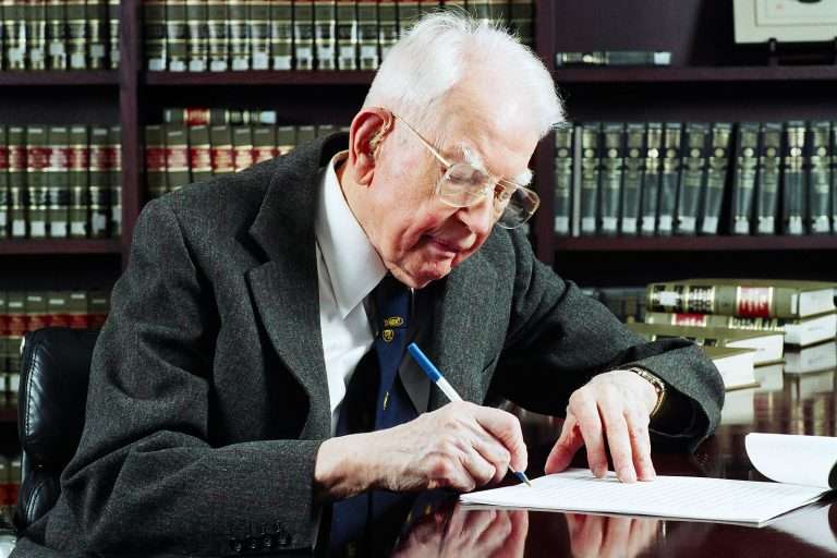 Ronald Coase working at a desk.