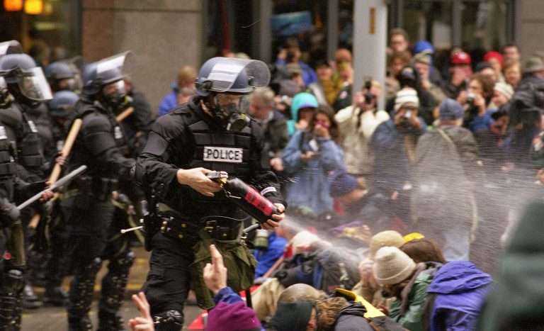 A police officer sprays pepper spray on protestors