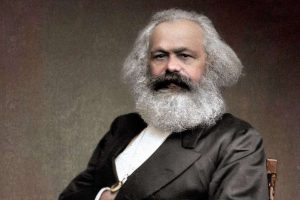 Karl Marx sitting in a chari.