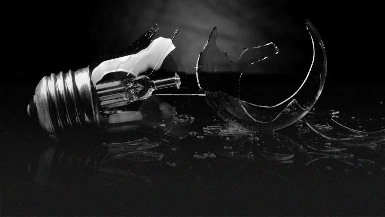 Black-and-white broken lightbulb on the ground.