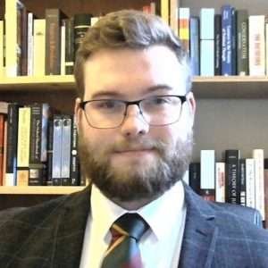 Jake Scott is a man with a beard wearing a suit
